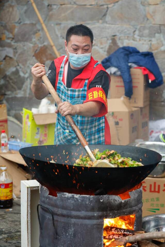 9月7日，贡嘎广场安置点内，一位志愿者在忙着炒菜。（新华社记者沈伯韩摄）