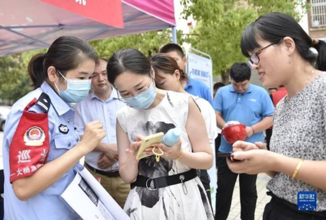 9月9日，在安徽省合肥市庐阳区大杨镇举办的2022年国家网络安全宣传周网络安全进社区活动上，民警为居民介绍防诈骗知识。新华社发（葛传红摄）