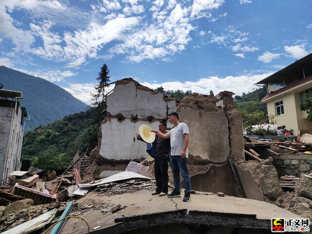 石棉县检察院干警周祖波(右)正在协助查看房屋倒塌受损情况。