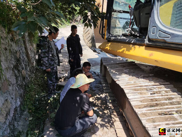 施工期间,一台挖掘机履带脱落,石棉县检察院党组书记、检察长羊辉正在和挖掘机师傅查看情况。