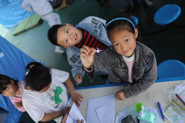 小朋友们在安置点内学习折纸。新华社记者刘琼摄