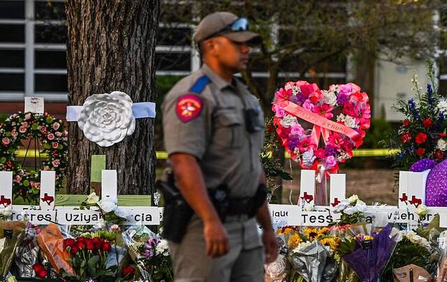 美国一名警察站在为罗布小学枪击案受害者设立的纪念碑附近。（资料图）