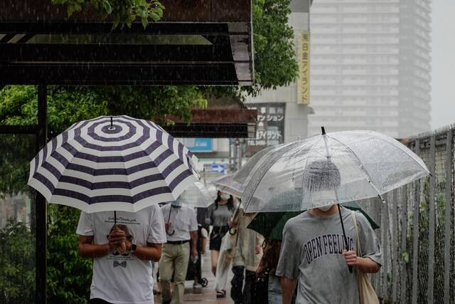 9月19日，行人在日本东京街头冒雨前行。（新华社记者张笑宇摄）