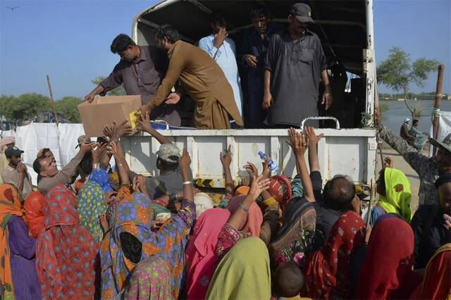 2022年9月17日，俾路支省贾法拉巴德县德拉阿拉亚尔镇，灾民们围绕着一辆护林队的卡车等待发放救济物资（视觉中国供图）
