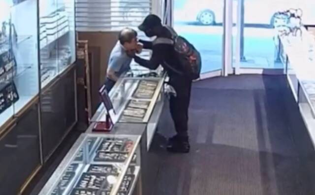 黑衣男子抓住美籍韩裔店主的脖子。