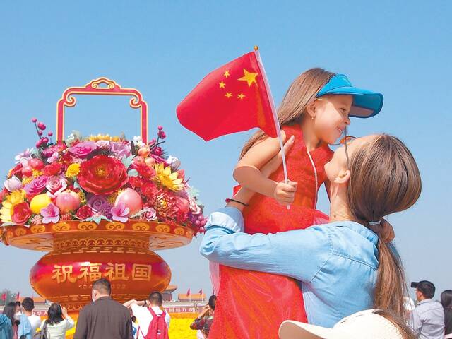 天安门广场上，一对母女在“祝福祖国”巨型花果篮前拍照留影。本报特约摄影杜建坡