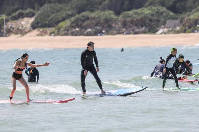 游客在海南三亚皇后湾海域体验冲浪运动。新华社记者张丽芸摄