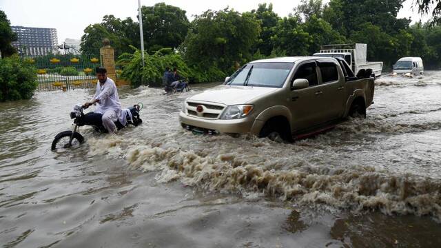 9月12日，在巴基斯坦卡拉奇，车辆在洪水中前行。新华社发