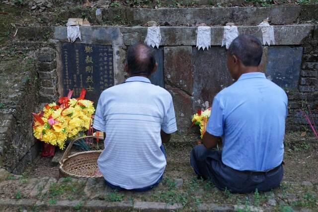 9月15日，谢南京和弟弟谢称发一起坐在邓毅刚烈士墓前，讲村里、家里的新变化。新华社记者周密摄