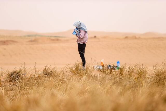 一名治沙工人在扎草方格间隙喝水（2020年8月27日摄）。新华社记者冯开华摄