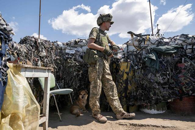 当地时间2022年7月23日，一名乌克兰士兵在一条狗的陪伴下，在米科勒夫地区的前线坚守阵地。人民视觉资料图