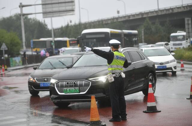 今天8点半，香泉环岛车流增长明显，交警在雨中疏导交通。新京报记者王贵彬摄