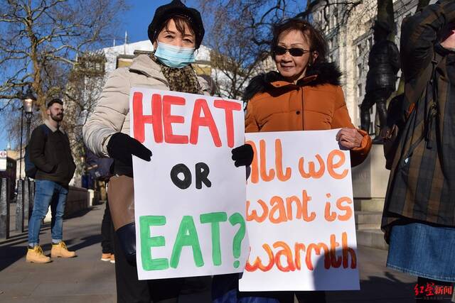 ↑伦敦民众手持“暖气还是食物？”“我们只想要温暖”的标语在街头抗议