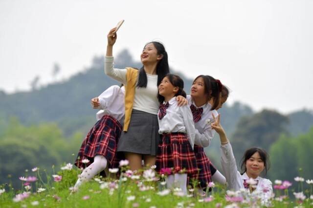 在江西省新余市分宜县洞村乡，老师钟琳珊（左二）带着合唱团的孩子在户外练歌玩耍，合影留念（2022年5月25日摄）。新华社记者彭昭之摄