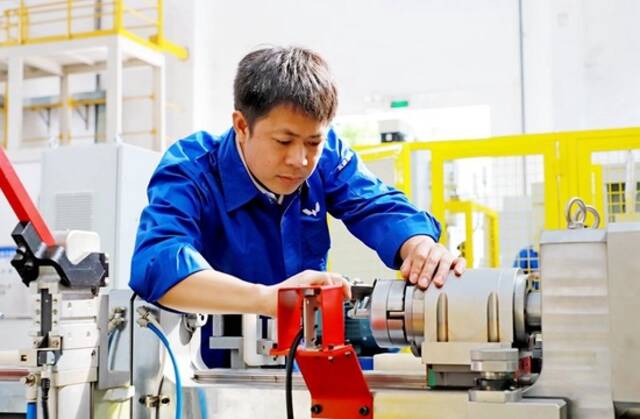 图片图为郑志明正在对衬套自动压装设备进行检测调试。柳州市委宣传部供图