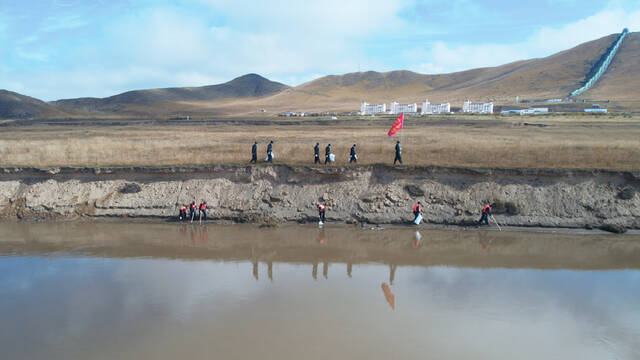 黄河护河队队员在岸边清理河中的漂浮垃圾。（无人机照片）新华社记者杨进摄