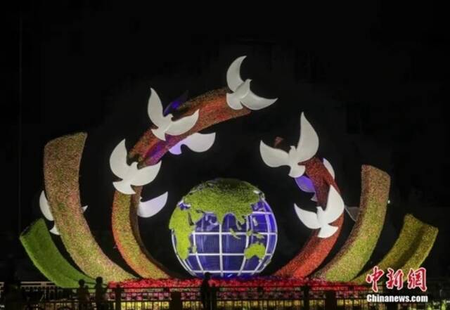 资料图：2022年9月26日晚，北京长安街沿线国庆主题花坛亮灯，市民在参观军事博物馆前广场布置的“命运共同体”花坛。中新社记者易海菲摄