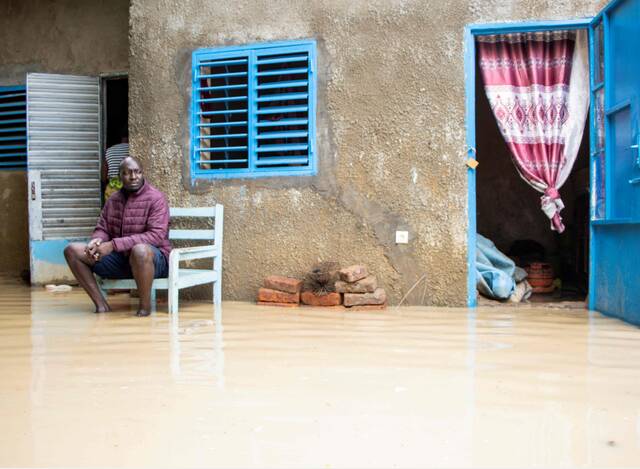 当地时间2022年8月5日，乍得恩贾梅纳，一名男子坐在被洪水淹没的房子内的院子里。（图片来源：视觉中国）
