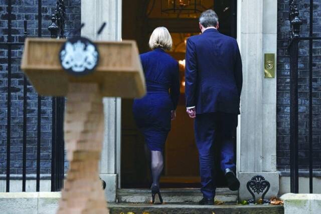 当地时间20日，英国首相特拉斯（左）在发表辞职声明后，与丈夫一起黯然走进唐宁街10号。（视觉中国）
