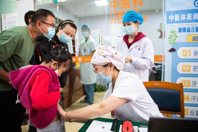10月21日，在湖南省儿童医院，中医医师（前排右一）正在为儿童贴药。新华社记者陈思汗摄