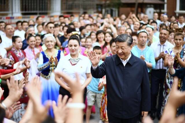 2022年7月13日，习近平在新疆维吾尔自治区乌鲁木齐市天山区固原巷社区考察时，向各族群众挥手致意。新华社记者燕雁摄