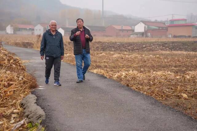 ▲10月26日，密云区大城子镇墙子路村，高克昌（左一）和王瑞胜走在村间小路上，他们边走边商量着今天的采访选题如何呈现。新京报记者王子诚摄