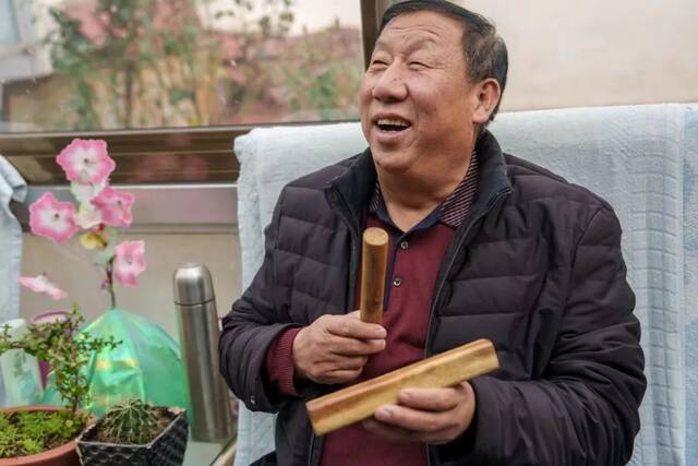 ▲10月26日，王瑞胜在采访间隙拿起村民的乐器梆子，开始互动。新京报记者王子诚摄