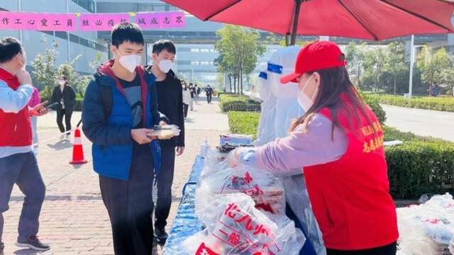 员工志愿者为上班同事发放公司提供的免费餐食