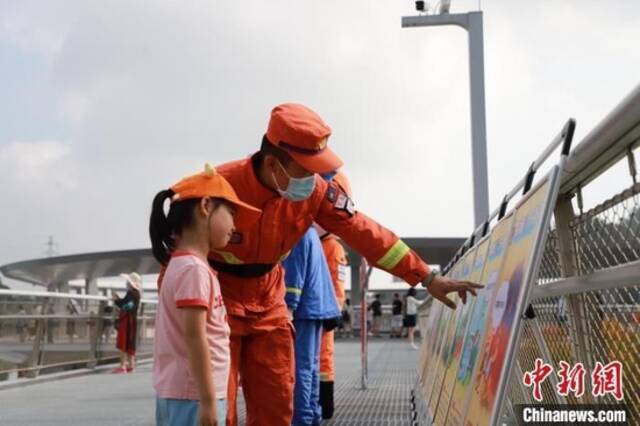 资料图：森林消防员正在防火宣传展板前与小朋友进行科普讲解。黄山鸿摄