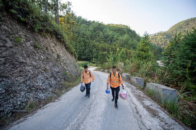 9月19日，看守员赵伟灯（右）与蔡金矿在前往赤岭隧道防洪值守点的山路上行走。