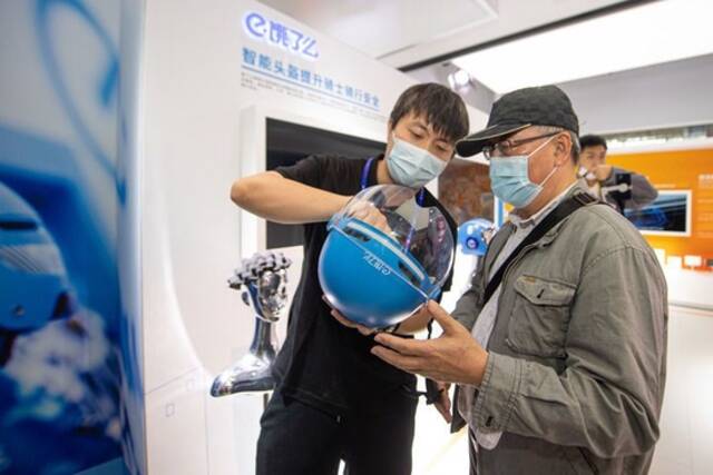 11月10日，阿里巴巴公司展台的工作人员向观众讲解智能头盔的工作原理。新华社记者江汉摄