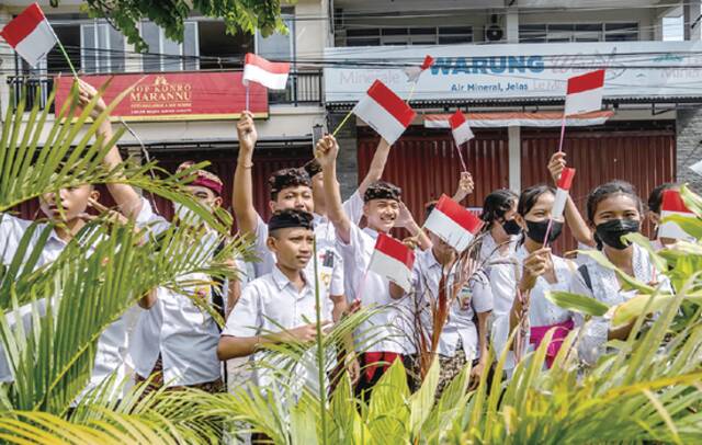 当地时间14日，印度尼西亚中学生挥舞印尼国旗欢迎前来参加G20峰会的代表。（视觉中国）