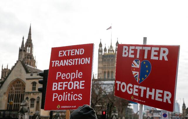 2020年12月9日，反对“脱欧”的示威者手举标语牌站在英国伦敦议会大厦外。新华社记者韩岩摄