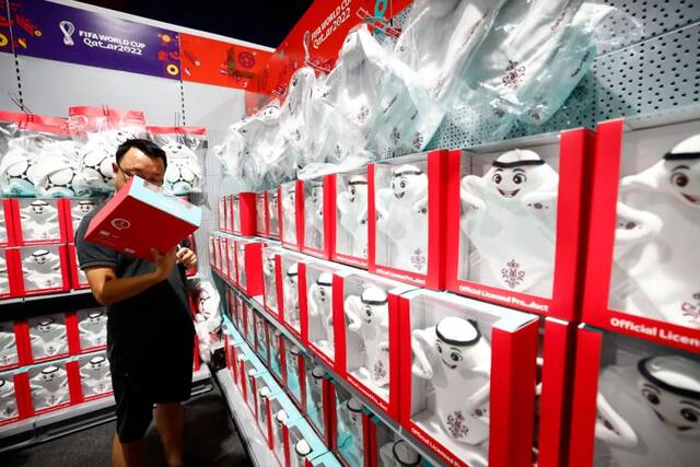 11月19日，卡塔尔多哈，球迷在2022卡塔尔世界杯纪念品商店选购本届世界杯吉祥物“拉伊卜”玩偶。图/中新社记者富田
