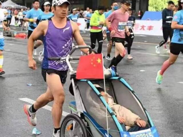10月20日，2022杭州马拉松赛事上，罗书坚推着儿子小柏奔跑在半程马拉松比赛赛场上。受访者供图