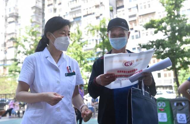 2022年7月6日下午，北京义诊现场，一名医生在为居民介绍医保政策。新京报记者李木易摄