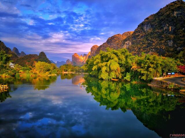 夕阳的余辉落在山头，泛起金光，遇龙河畔的凤尾竹依旧苍翠婀娜，蓝天碧水浑然一色。（阳朔县纪委监委莫品良/摄）