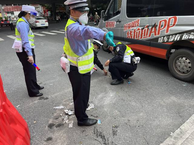 （交警拆除地面上的螺丝为机动车通行扫除障碍第一财经记者吴绵强摄）