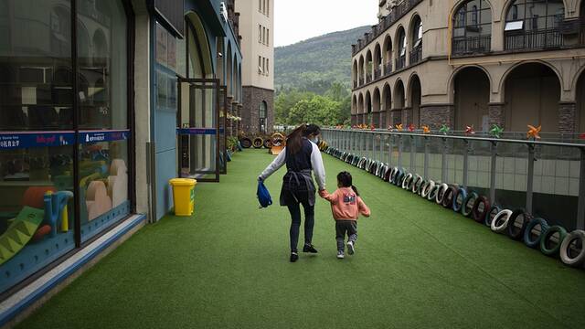 四川省广元市利州区优培托育中心，在托育人员的牵引下，一个小女孩欢快地走向自己的教室。人民视觉资料图