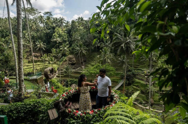 当地时间2022年12月8日，印尼巴厘岛，一对外国游客在竹甲板上准备拍照。图/视觉中国
