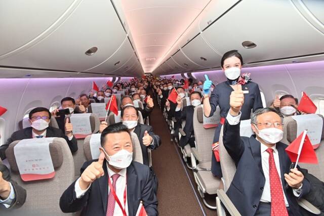参加交付航班的旅客在客舱中挥舞国旗