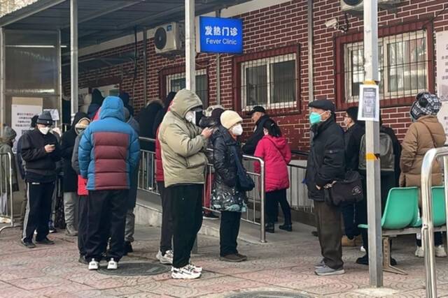  2022年12月14日，北京，在新冠疫情期间，人们在一家发烧诊所外排队。（图