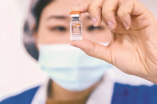 ▲2020年12月23日，科兴中维的工作人员在包装车间展示西林瓶包装新冠病毒灭活疫苗。图/新华社
