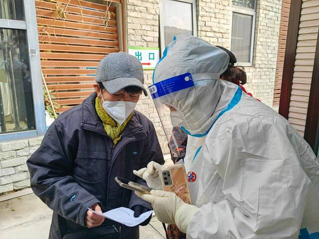 12月19日，护士高丽梅（右一）在成都市武侯区玉林社区卫生服务中心发热诊室前对就诊患者进行分流指导。新华社记者董小红摄