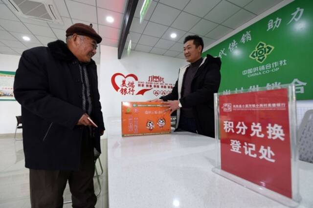 在安徽省滁州市凤阳县小岗村，村民缪守鲁（左）在村里“美德银行”用积分兑换生活物品（2021年1月30日摄）。新华社记者周牧摄