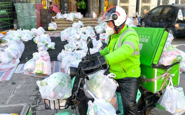 2022年12月17日，北京，东城区东土城路一家美团买菜配送点忙碌的送货快递小哥。（图