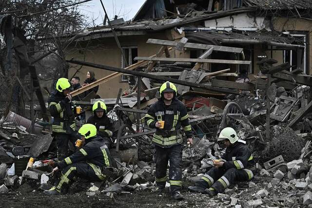 当地时间2022年12月29日，乌克兰基辅，导弹袭击后，救援人员在清理被摧毁的房屋废墟后休息。图/视觉中国