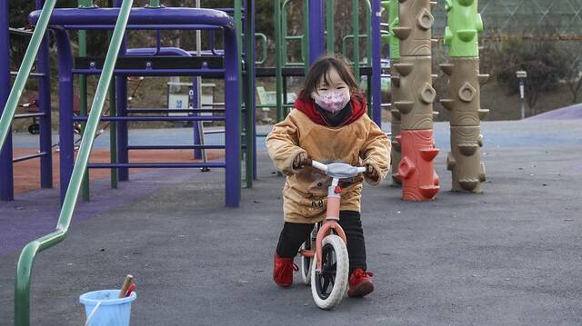 2022年12月14日，江苏淮安，一名小朋友戴着口罩在九龙湖体育公园骑平衡车。视觉中国图
