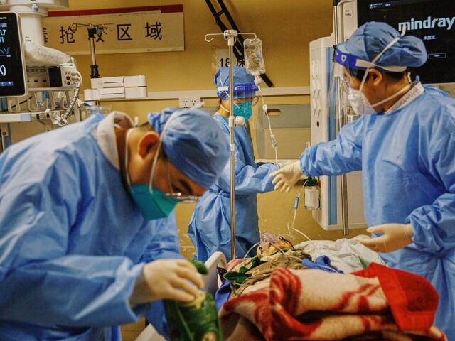 2022年12月27日晚，朝阳医院急诊科抢救室，医务人员为一名送抵抢救室的患者供氧、安装监测仪器。新京报记者郑新洽摄