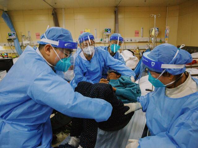 2022年12月27日晚，朝阳医院急诊科，医务人员合力将送抵抢救室的患者从担架挪至病床。新京报记者郑新洽摄